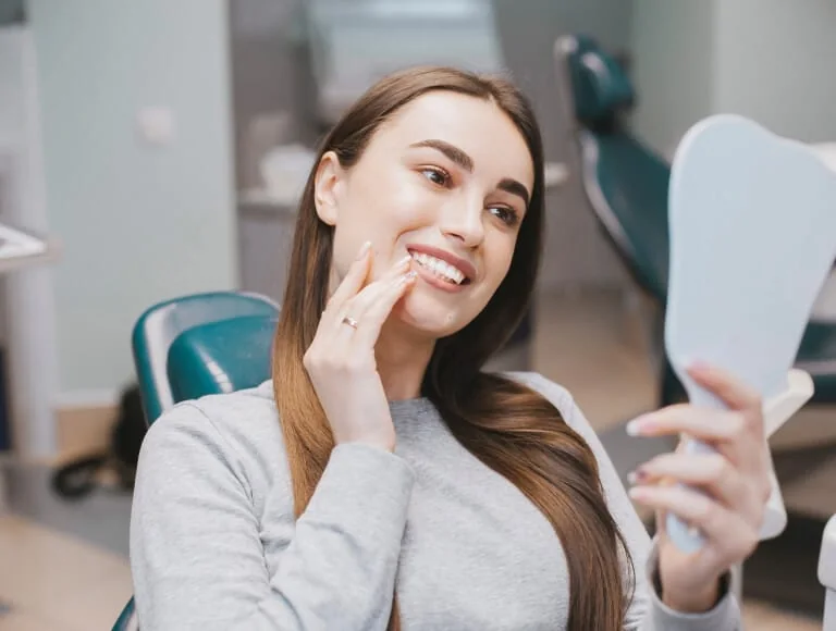 Patient admiring her new smile in a hand mirror