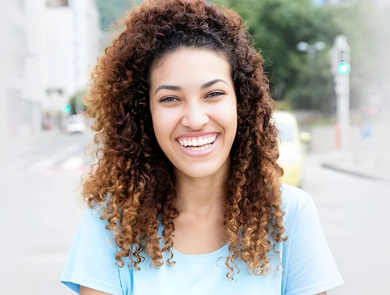 Woman with curly hair smiling outdoors